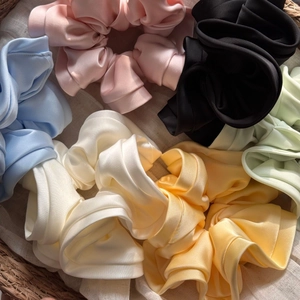 Detailed close-up of a variety of colorful satin scrunchies with elegant ruffled edges