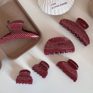 Detail of assorted hair claw clips featuring red plaid patterns and strawberry prints