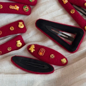 Close-up of red velvet New Year hair clips with gold coin and lucky bag decorations