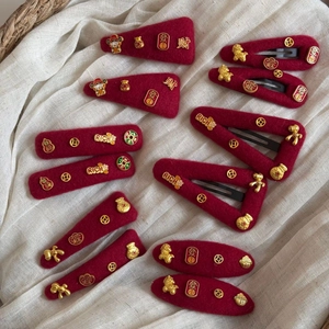Detail of red velvet Chinese New Year hair clips with gold lucky charms and characters