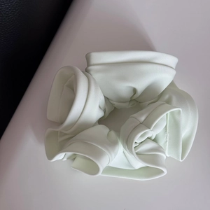 Detailed view of light mint green satin scrunchie with ruffled texture and glossy fabric
