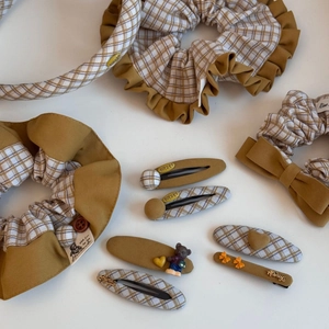 Detail showing mustard yellow fabric scrunchies and hair clips with cute bear charms