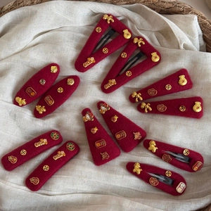 Macro detail of red felt New Year hair clips with gold RICH and fortune coin charms