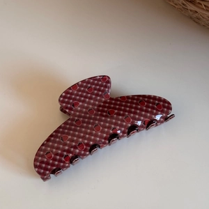 Detail view of a strawberry hair claw clip featuring red checkered patterns on acrylic