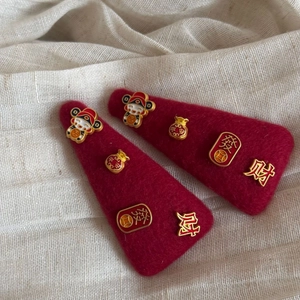 Detail of red New Year BB hair clips with gold lucky bag and Fortune character charms