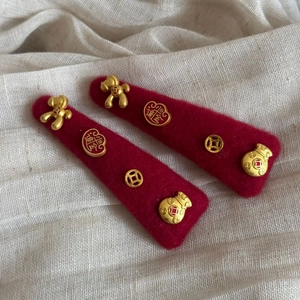 Detailed close-up of red felt hair clips featuring golden Chinese zodiac horse and lucky charms