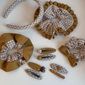 Flat lay of retro mustard yellow and plaid fabric hair accessories set on white background