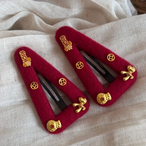 Detail of red plush hair clips with gold RICH letters and lucky bag metal accents