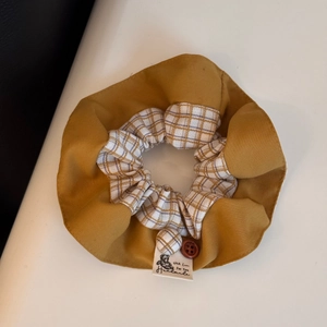 Detail of handmade fabric scrunchie with ginger yellow fabric and cute bear logo label