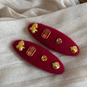 Detail of red felt hair clips featuring golden dragon, fortune coins and lucky symbols