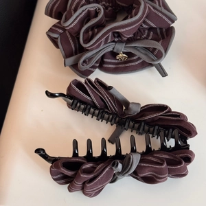 Dettaglio dell'elastico a righe caffè e fermaglio nero con finiture grigie