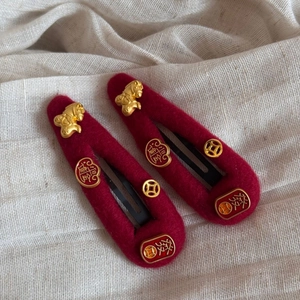Detail of red felt hair clips with golden charms featuring festive Chinese characters
