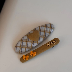 Detail of plaid fabric hair clips set featuring a heart charm and orange bows with Always tag