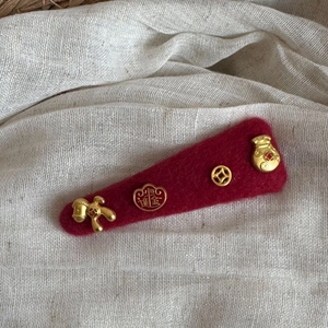 Detailed shot of dark red felt hair clip with golden Chinese New Year lucky charms