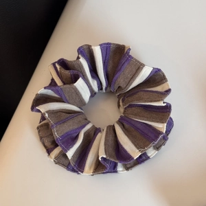 Dettaglio dell'elastico in tessuto a righe viola, bianco e marrone con trama increspata