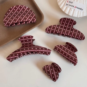 Détail de pinces à cheveux bordeaux avec motifs de cœurs de différentes tailles