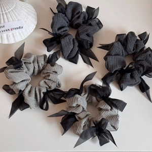 Detail view of four velvet scrunchies with grey patterns and sheer organza bows