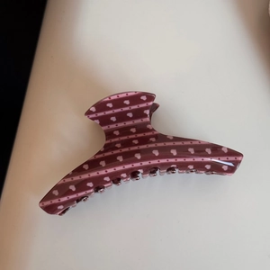 Détail macro d'une pince à cheveux brun rouge avec cœurs roses et motifs de lignes