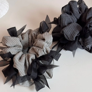 Detailed close-up of grey striped and plaid scrunchies with black mesh bows
