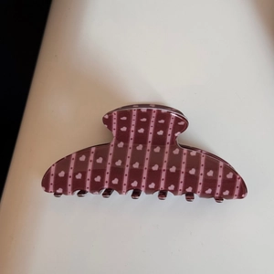 Détail de la grande pince à cheveux bordeaux avec cœurs roses et motifs rayés