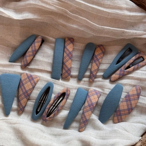 Close-up of fabric plaid and solid blue hair clips set in various geometric shapes