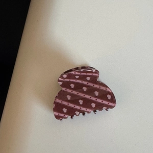 Grosse pince à cheveux marron avec motifs cœurs roses et pois en gros plan
