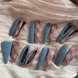 Detail view of colorful fabric plaid and denim blue snap hair clips in various shapes