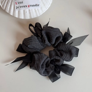 Detail of grey knitted scrunchie with sheer ribbon bow and textured fabric finish