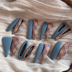 Detail view of 16-piece fabric wrapped snap hair clips in blue and plaid patterns