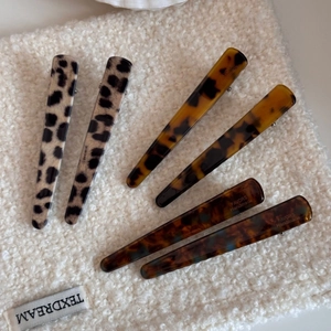 Detail of 6-piece French leopard hair clip set with acetate finish on white wool background