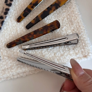 Close-up of leopard and tortoiseshell acetate hair clips on soft white fabric background