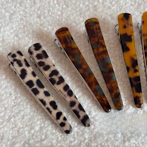 Close-up of leopard and tortoiseshell acetate duckbill clips on soft cream fabric