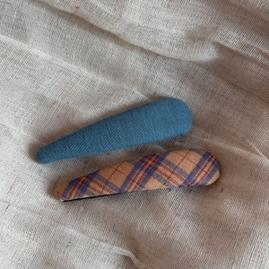 Detail of plaid fabric BB hair clips set on a beige aesthetic textured background