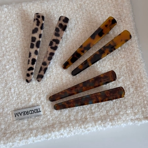 Detailed top view of leopard and tortoise shell pattern hair clips on white fleece texture