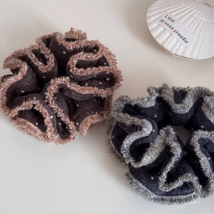 Dettaglio di elastici scrunchie in maglia con bordi pelosi e pois su sfondo bianco