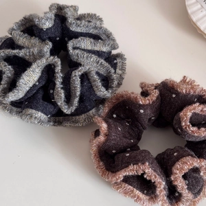 Dettaglio di due elastici per capelli in peluche a pois con bordi in pizzo metallico lucido