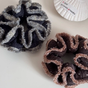 Dettaglio ravvicinato di elastici in peluche grigio e marrone con glitter e bordo oro
