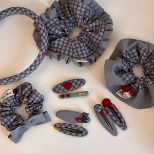 Flat lay of gray plaid fabric scrunchies and hair clips with vintage button accents