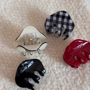 Detailed close-up of four checkered and solid colored acetate hair claws on soft fabric