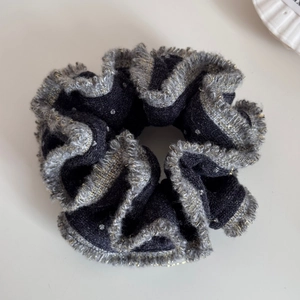 Dettaglio di elastico per capelli in maglia nera con bordo glitter argento e trama morbida