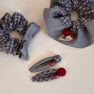 Flat lay of retro blue plaid scrunchies and decorative hair clips on white surface