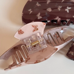 Détail de pinces à cheveux papillon en acétate marron et rose avec ressorts dorés fins