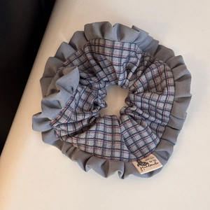 Macro shot of British plaid fabric scrunchie with grey ruffled edge and handmade cloth label
