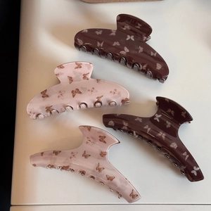 Quatre pinces à cheveux à motif papillon en marron et rose sur fond neutre uni