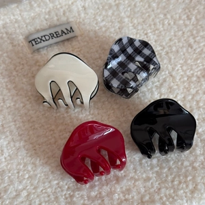 Set of four checkered and solid acetate hair claws on a cozy white plush background