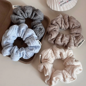 Detail of twisted knit headbands in grey, blue, and khaki with woven brand label