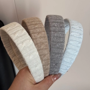 Detail showing set of four braided knit headbands in cream, khaki, grey and light blue