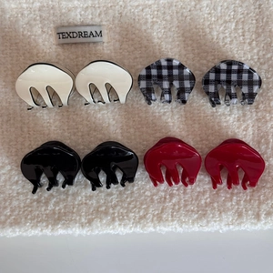 Eight mini plaid and solid color acetate hair claw clips on soft textured fabric