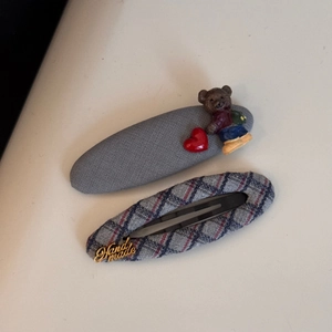 Detail of fabric hair clips with a cute 3D bear ornament and Handmade metal logo plate