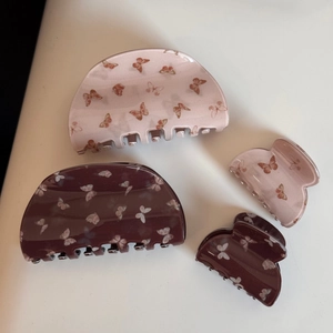 Détail de pinces à cheveux rose et bordeaux ornées de motifs délicats de papillons
